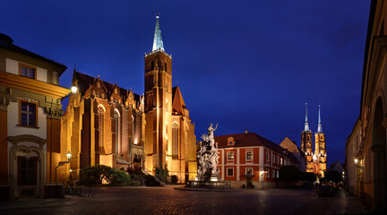 Fototapeta na wymiar The evening wiew of the church of the Holy Cross and the twin towers of St. John's cathedral in the oldest part of Wroclaw (called Tumski Island), Poland