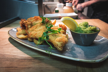 Deep fried haddock fillet served with triple cooked chips and mushy peas, garnished with a lemon wedge and micro herbs.