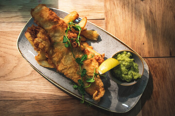 Deep fried haddock with triple cooked chips and mushy peas, garnished with lemon and micro herbs.