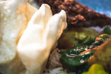 A chicken curry served with basmati rice, poppadum's and onion bhajis, garnished with viola flowers and micro herbs.