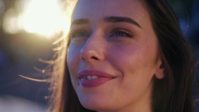 Close-up shot of a pretty young girl's face in sunlight. 4K.