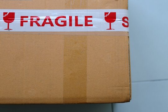 Fragile tape sticker on the brown cardboard parcel box, Warning the cargo, be careful not to break the product.