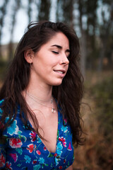 outdoor portrait of a beautiful brunette woman in dress with red flowers in her hair in the field.