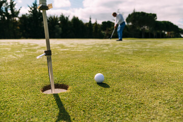 Fototapeta na wymiar Senior golfer following golf ball to hole