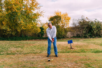 Portrait of senior golfer ready to hit the ball in autumn