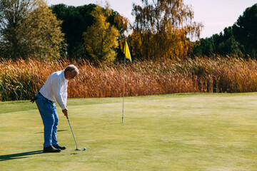 Senior golfer standing on the green ready for holing