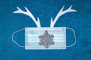 Festive Christmas background with deer antlers and medical face mask. New Year 2021