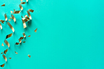 close up on group of gold color of rolling ribbon and confetti on teal background with copy space for christmas festival happy new year ,carnival , birthday and anniversary, concept design	