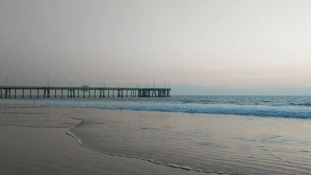 Venice Beach pier at sunset with low tide shoreline, Los Angeles static shot