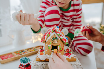 Children decorated Christmas gingerbread house on the table