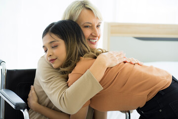 Obraz premium senior caucasian sick woman on wheelchair in hospital with mixed race daughter close relationship. Healthcare and medicine concept. virus pandemic concept. 