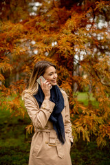 Young woman using mobile phone in the autumn park