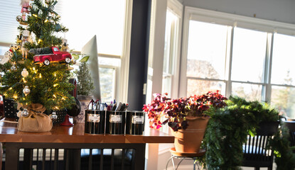 Fototapeta premium Multitasking while telecommuting. Computer sitting on a cherry stand up desk with Christmas tree on a sunny day with giant pot of shamrocks in background and a large wreath awaiting decoration.