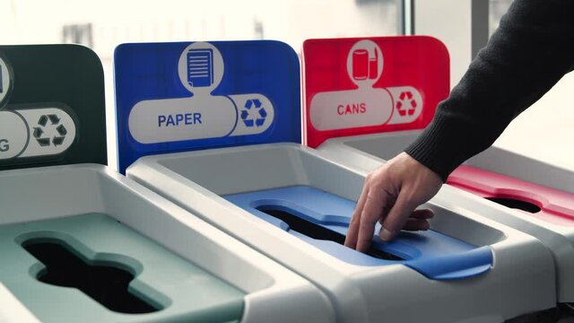 Close-up of man throwing garbage into sorting bins. Media. Man throws garbage into colored bins for sorting. Sorting garbage helps in recycling and supports ecology of nature