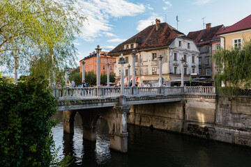 Fototapeta na wymiar The iconic Cobblers bridge in Ljubljana with Ljubljanica river and old house in background on sunny day