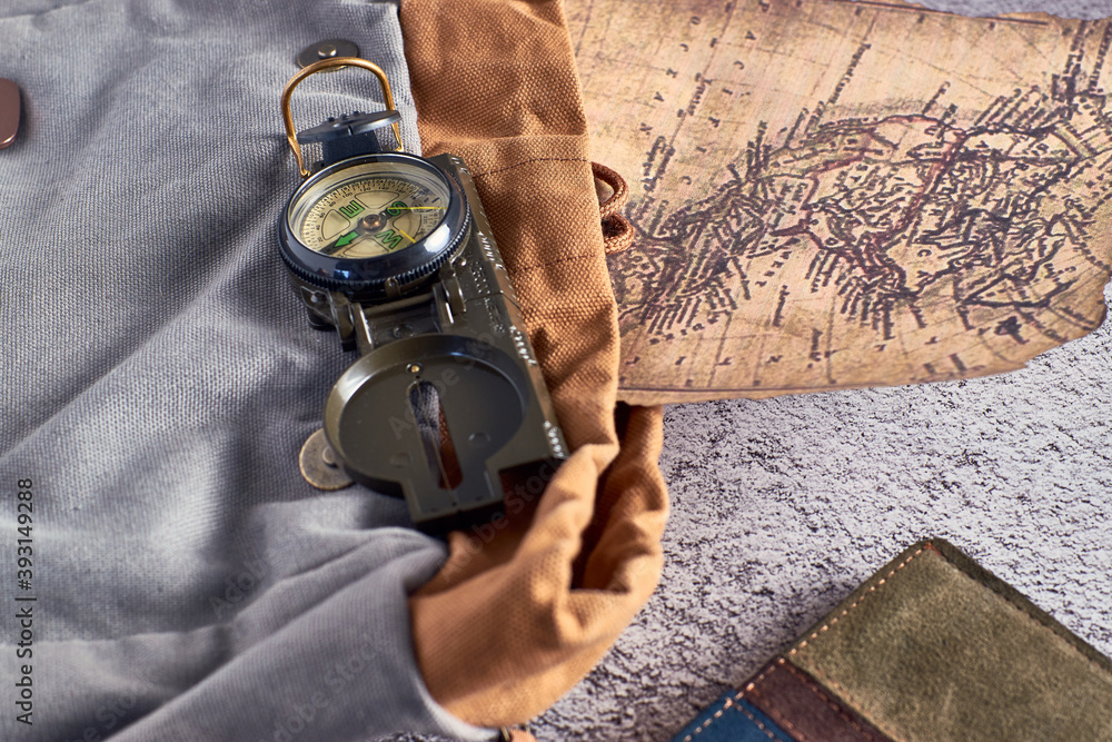 Poster top view closeup of a compass placed on a colorful fabric next to an ancient map