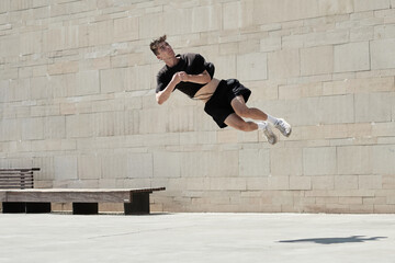 Upside down of young male doing somersault while practicing parkour in urban area in summer