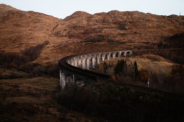 Breathtaking scenery of winding Glenfinnan Viaduct leading through mountains in Scottish Highlands in autumn