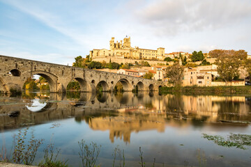 Obraz premium Vue depuis les rives de l'Orb sur la cathédrale Saint-Nazaire de Béziers au coucher du soleil (Occitanie, France)