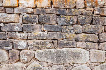 Wall of thick ancient rocks, rustic background of medieval construction.