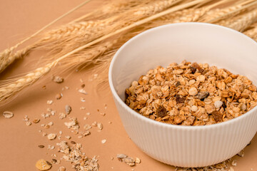 Deep bowl of cereal on a brown background. A healthy concept for breakfast, nearby are ears of wheat. copy space. 