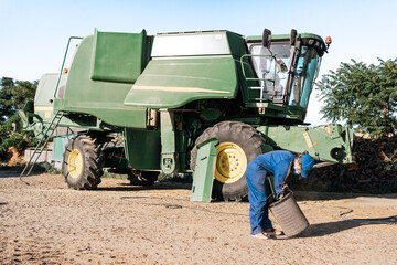 Side view of unrecognizable farmer in workwear cleaning filter of agricultural combine harvester in farm yard