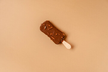Ice cream on a stick in chocolate glaze on a brown background. Copy space.