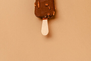 Ice cream on a stick in chocolate glaze on a brown background. Copy space.
