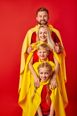 family of superheroes, friendly parents with son and daughter pretend to ber superheroes. look at...