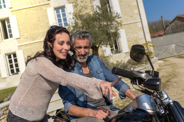 Fototapeta na wymiar husband introduces his new custom motorbike to his wife