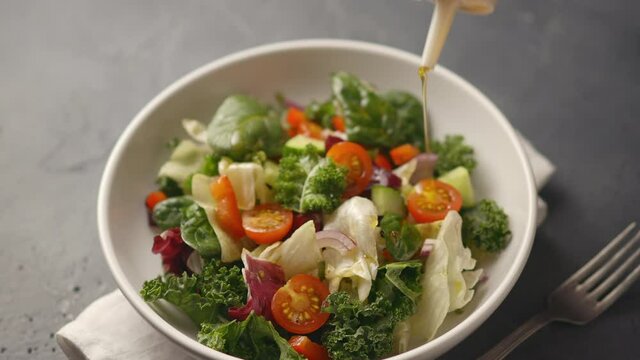 The cook pours a juicy healthy vegetable salad with olive oil, the camera moves to the salad. Cucumbers, tomatoes, lettuce, iceberg lettuce. close-up