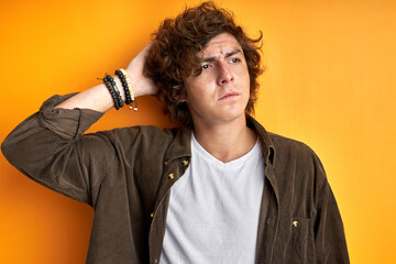 thoughtful man touch hair isolated on orange background, think about something, stand in contemplation