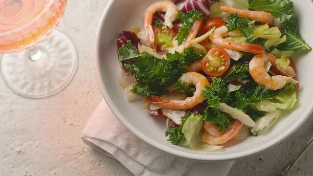 A juicy healthy vegetable salad with king prawns is peppered by the chef. Iceberg lettuce, frillis, olive oil, pepper, salt. close-up