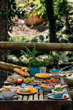 From above of old wooden table with assorted dishes served for cozy picnic in forest in Valle del Jerte