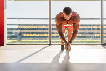 Strong sportsman doing push ups with effort and clapping hands while training in gym