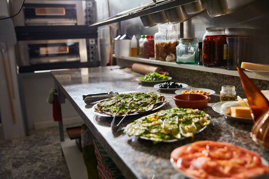 Top view of various fresh ingredients for pizza making on marble table in restaurant kitchen