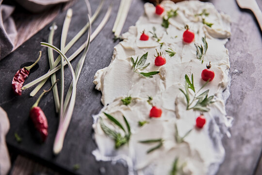 From above of tasty cream cheese and pieces of fresh bread arranged with various herbs on slate board on wooden table