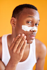 beauty procedure and skin care, young black manful man with face mask on around nose zone, isolated over yellow background