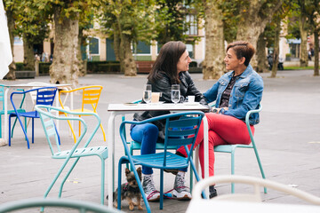 Middle aged lesbian couple with their dog in a cafe terrace