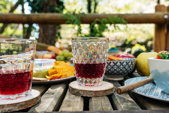 Glasses with delicious grape juice served on wooden table with various food for picnic in forest in Valle del Jerte