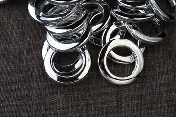 Glossy nickel-plated or chrome-plated Eyelets for attaching curtains in the design workshop.