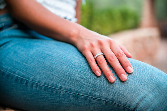 Crop anonymous female with elegant engagement ring sitting in park in summer at weekend