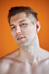 Obraz premium portrait of handsome caucasian guy with transparent patches for dark circles under eyes, enjoy and relax isolated over yellow background