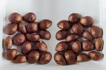 Two heaps of medlar fruit tree seeds in an elegant white ceramic plate. Health & Wellness.