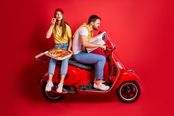 Fototapeta na wymiar delivery man at work with girlfriends, confident courier is delivering orders on motorbike, while his redhead girlfriend is eating pizza in the back seat. isolated red background