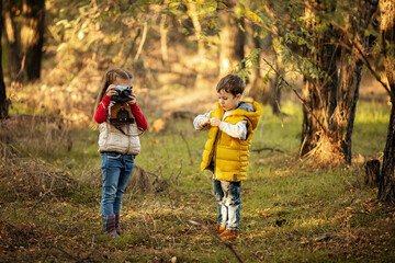 cute boy and girl 4 years old play with an old film camera and take pictures of each other