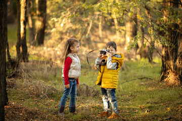 cute boy and girl 4 years old play with an old film camera and take pictures of each other