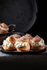 Homemade profitroles pastry filled with custard on dark background