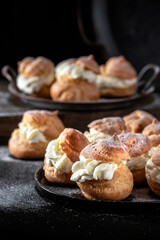 Homemade profitroles pastry filled with custard on dark background