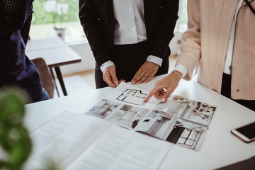 Midsection of woman pointing at magazine by real estate agent in new house